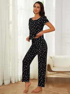 Detail view of women's black two-piece pajama set featuring white heart pattern print