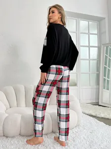 Back view of model wearing black pajama top and plaid pants in a cozy living room setting