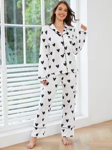 Woman posing in a white pajama set with black heart print near a bright window