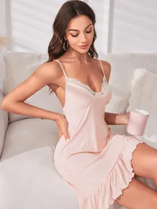 Nuisette sexy rose à bretelles avec dentelle blanche et ourlet à volants sur un mannequin assis