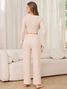 Back view of a ribbed beige two-piece loungewear set with cropped top and wide pants.