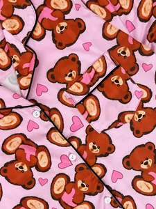 Detail of pink pajamas with cute brown bear and heart patterns and black piping trim