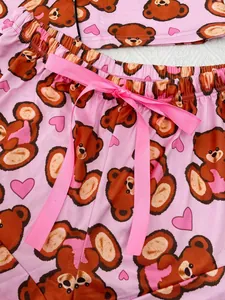 Detail view of pink pajama shorts featuring cartoon bear prints and a ribbon bow