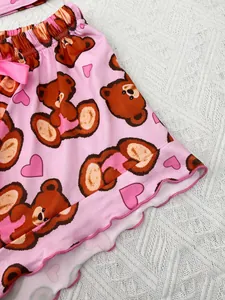 Close-up of pink pajama shorts featuring cute bear and heart print with lettuce hem