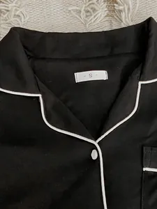 Detail shot of a black pajama collar with white piping and small size S label.
