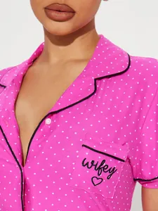 Close-up of pink polka dot pajamas with 'wifey' embroidery and black trim