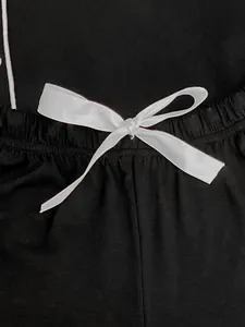 Close-up of the elegant white satin bow detail on black elastic waistband of women's pajamas