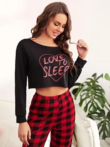 Close-up view of heart print long sleeve crop top and red plaid pajama pants on model
