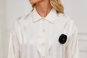 Detail view of champagne striped satin pajama shirt featuring an elegant black rose brooch