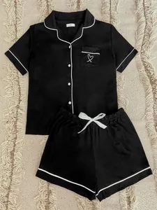 Close-up of elegant black summer pajama set featuring white piping and heart pocket detail