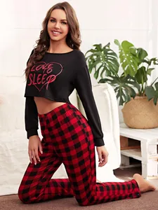 Detail of two-piece pajama set with Love to Sleep crop top and red plaid pants.