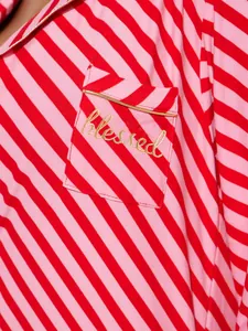 Close-up of red and pink striped pajamas with gold 'blessed' embroidery on the pocket