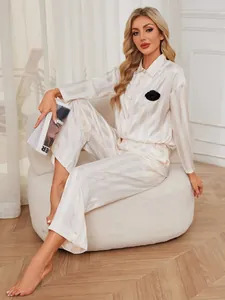 Elegant champagne striped satin pajama set with long sleeves and black flower detail.