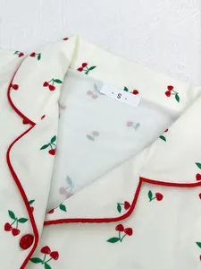 Close-up of white pajama shirt collar with red cherry print and piping