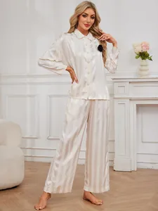 Detail shot of woman posing in elegant striped silk-like loungewear set in a home setting