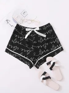 Detailed view of black women's pajama shorts with white script print and satin bow tie