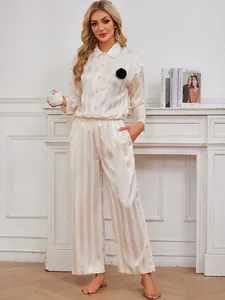 Full detail view of women's champagne striped satin pajama set with black flower