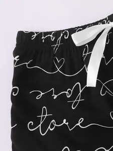 Detail of black lounge shorts featuring white cursive heart print and ribbon bow