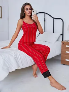 Sexy red striped pajama set with camisole top and lace cuff pants on a white bed.