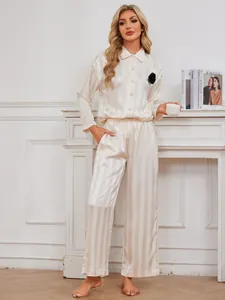 Elegant cream striped satin pajama set featuring long sleeves and a black floral detail