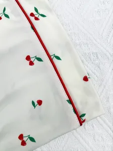 High-quality close-up detail of women cherry print pajama set with elegant red satin piping
