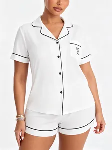 Close-up of white women's pajama set featuring black piping and heart embroidery.