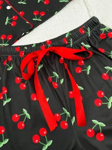 Close-up detail of a soft black pajama set with red cherry print and decorative bow