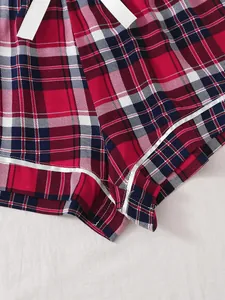 Close-up detail of red plaid women's pajama shorts featuring white piping and drawstring.