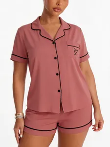 Detailed view of pink faux modal pajama set featuring black piping and heart embroidery