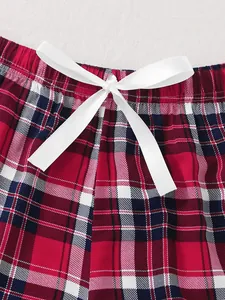 Detailed view of the elegant white satin bow on red and blue plaid pajama shorts