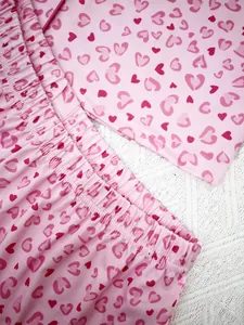 Detailed view of pink heart-print pajama fabric showing texture and elastic waistband