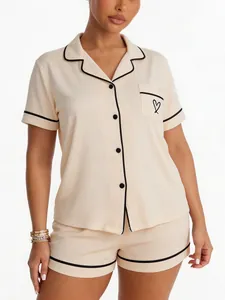 Detail view of cream short-sleeve pajama set with black piping and heart embroidery