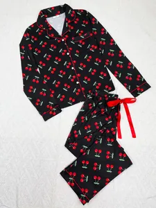 Flat lay of black cherry print pajama set with long sleeves and red ribbon detail