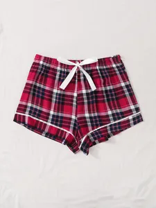 Detailed close-up view of women's red plaid pajama shorts with white bow and trim.