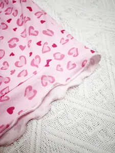 Close-up of pink pajamas with heart print and ruffle lettuce edge detail for women