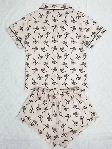 Detailed view of pink two-piece pajama set with black bow print and contrast piping