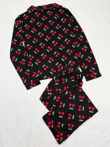 Detail view of black women's pajama set featuring a vibrant red cherry print and lapels.