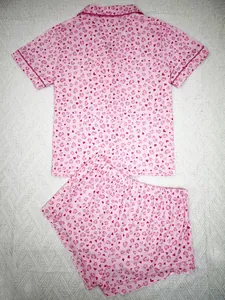 Detailed flat lay of pink two-piece pajamas with an all-over heart print pattern.