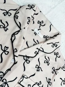 Close-up detail of pink women's pajama top with black bow pattern and elegant piping detail