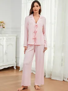 Elegante Ganzkörperaufnahme eines rosa zweiteiligen Pyjama-Sets mit Schleifen und langer Hose