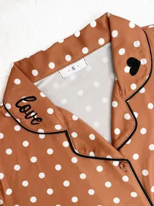Detail view of brown polka dot pajama top with 'love' embroidery on lapel collar
