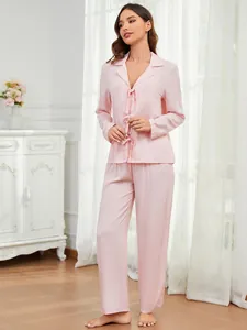 Elegantes, zartrosa, langärmeliges Pyjama-Set, an einem Model in gemütlichem Heim