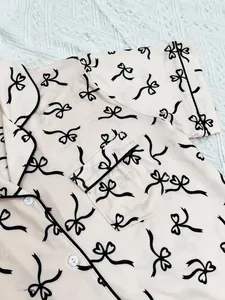 Detail of pink women's pajama top featuring black bow patterns and piping detail.