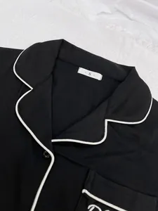 Vue détaillée du col et de la poche d'un pyjama noir pour femme avec un liseré blanc élégant.