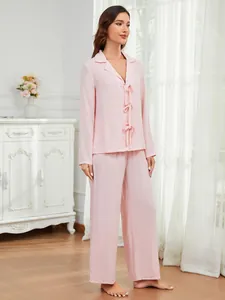 Elegantes hellrosa zweiteiliges Damen-Loungewear-Set mit langen Ärmeln und Schleifendetails.