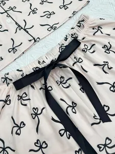 Detail view of pink women's pajama set featuring a black bow pattern and decorative waist tie