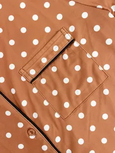 Detail shot of brown polka dot nightwear fabric featuring a pocket and button design