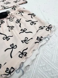 Close-up view of pink pajama shorts featuring black bow print and ruffled hem details.