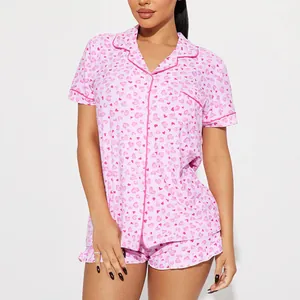 Pink heart print two-piece summer pajama set with short sleeves and ruffled shorts for women.