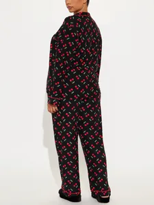Rear view of women's black long-sleeved pajama set with red cherry print details.